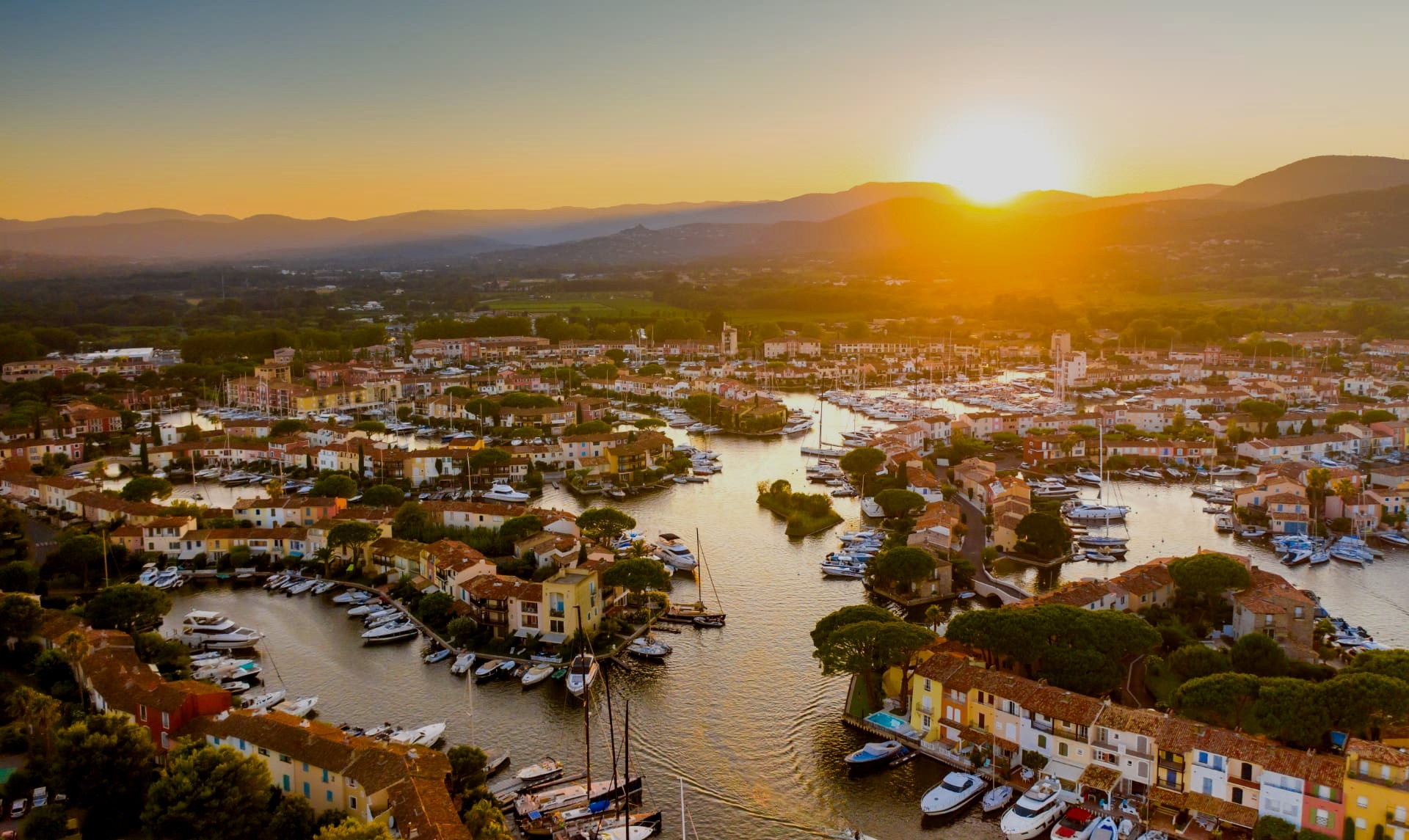 Les canaux de Port Grimaud à la lumière du soir, bordés de maisons pastel et de bateaux traditionnels